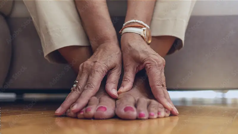 Close up of senior woman hands touching legs with varicose veins.