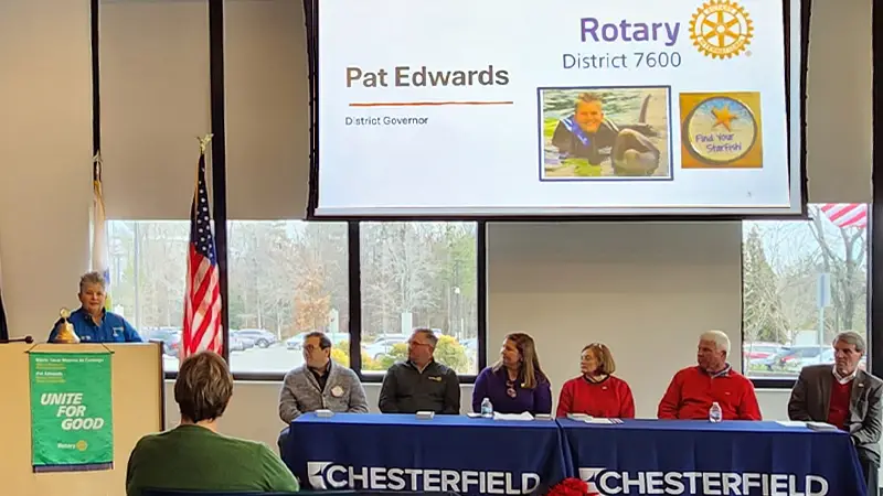 Press conference, Speaker at the podium, panel of community leaders seated at a table in the conference room.